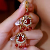 Pair of Chinese red ruyi lock dangle earrings, gold rhinestone drop earrings held in hand
