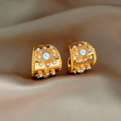 Vintage gold floral pearl wide hoop earrings on beige satin background
