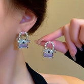 Pair of cute purple mini handbag pearl stud earrings, worn on ear and held for detail