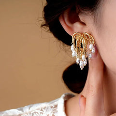 Close up of gold pearl chandelier drop earring worn on woman's ear