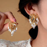 Statement vintage gold pearl chandelier earrings: one worn on ear, one held in hand