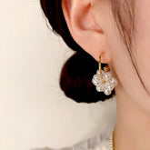 Gold hoop pearl flower earring worn on female ear, close-up product shot