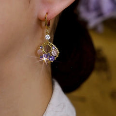 Close-up of vintage gold purple crystal cat's eye dangle hoop earring worn on ear