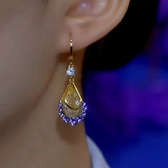 Gold purple crystal teardrop dangle earring on female ear, front angle close-up