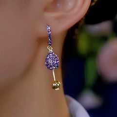 Purple crystal teardrop gold ball drop hoop earring worn on ear