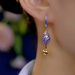 Side view of purple pave teardrop gold ball dangle hoop earring on ear