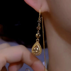 Champagne gold crystal teardrop dangle earring on ear, front view close-up