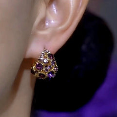 Gold purple rhinestone triangular stud earring worn on earlobe
