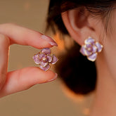 Purple enamel flower stud earring held by hand, matching earring worn on ear