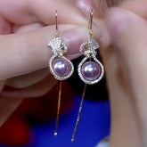 Pair of purple pearl crystal-studded gourd tassel drop earrings held between fingers