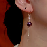 Close-up of women's purple pearl long tassel dangle earring worn on ear