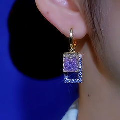 Women's gold purple and blue square crystal drop earring worn on left ear