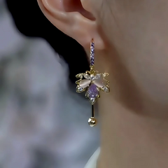 Gold purple floral crystal dangle earring worn on woman's ear