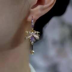 Side view of purple crystal gold floral drop earring on ear
