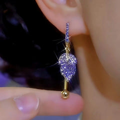 Close-up of purple rhinestone leaf gold drop earring on ear