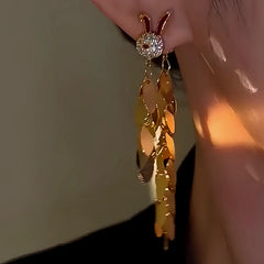 Close-up of gold rabbit leaf tassel dangle earring worn on ear