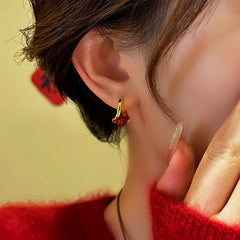 Dainty gold red bead small hoop earring closeup on woman's ear