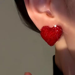 Close-up of red glitter heart stud earring worn on ear