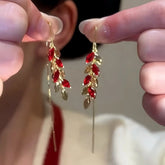 Pair of gold red zircon leaf long ear threader drop earrings held between fingers