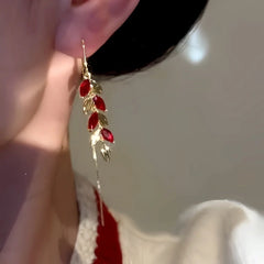Close up of red zircon leaf gold ear threader drop earring on ear
