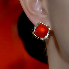 Red gemstone gold crystal stud earring worn on a woman's ear