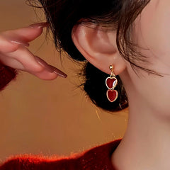 Model showcasing the dangle and style of the 14K Gold-Plated Red Double Heart Earrings