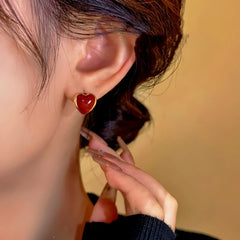 Model showcasing the dangle and style of the 14K Gold-Plated Red Heart Hoop Earrings