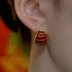 Model showcasing the dangle and style of the 14K Gold-Plated Red Oil Drop Bag Earrings