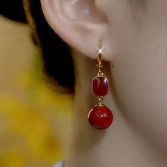 Model showcasing the dangle and style of the 14K Gold-Plated Red Pearl Earrings