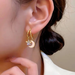 Model showcasing the dangle and style of the 14K Gold-Plated Star And Moon Earrings