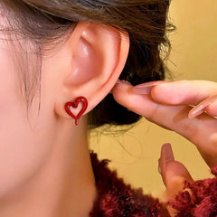 Model showcasing the dangle and style of the 14K Gold-Plated Wine Red Heart Stud Earrings
