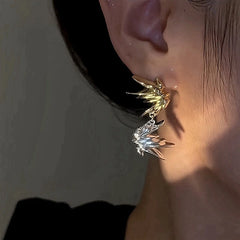 Two-tone gold silver spiky starburst drop earring worn on ear, side close-up
