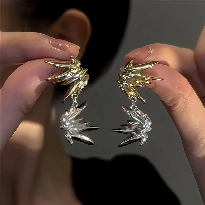 Pair of two-tone gold silver spiky starburst statement drop earrings held in hands