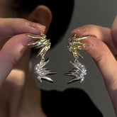 Pair of two-tone gold silver spiky starburst statement drop earrings held in hands