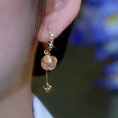 Model showcasing the dangle and style of the 14K Gold-Plated Zircon Cat's Eye Stone Ball Tassel Earrings