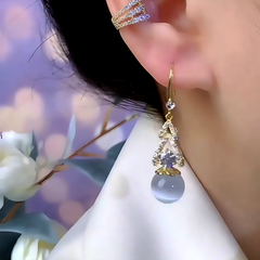 Model showcasing the dangle and style of the 14K Gold-Plated Zircon Cat's Eye Stone Bead Ear Hook Earrings