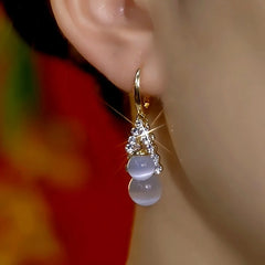 Model showcasing the dangle and style of the 14K Gold-Plated Zircon Cat's Eye Stone Bead Earrings