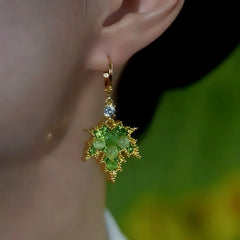 Model showcasing the dangle and style of the 14K Gold-Plated Zircon Cat's Eye Stone Green Maple Leaf Earrings