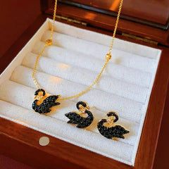 Model showcasing the dangle and style of the 14K Gold-Plated Zircon Crown Black Swan Earring And Necklace Set