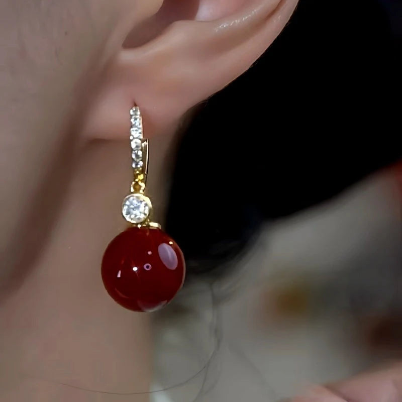 Model showcasing the dangle and style of the 14K Gold-Plated Zircon Diamond Red Pearl Earrings