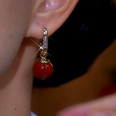 Model showcasing the dangle and style of the 14K Gold-Plated Zircon Diamond Red Pearl Earrings