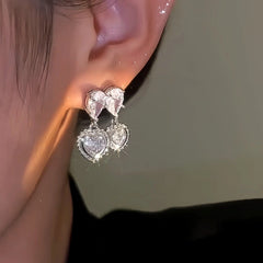 Model showcasing the dangle and style of the 14K Gold-Plated Zircon Double-Heart Earrings