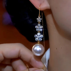 Model showcasing the dangle and style of the 14K Gold-Plated Zircon Flower Pearl Threader Earrings