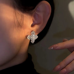 Model showcasing the dangle and style of the 14K Gold-Plated Zircon Four-Leaf Flower Stud Earrings