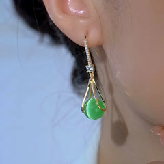 Model showcasing the dangle and style of the 14K Gold-Plated Zircon Green Cat's Eye Bead Ear Hooks