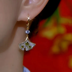 Model showcasing the dangle and style of the 14K Gold-Plated Zircon Green Diamond Ginkgo Leaf Earrings
