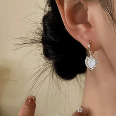 Model showcasing the dangle and style of the 14K Gold-Plated Zircon Heart Bow Earrings