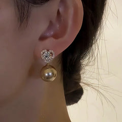Model showcasing the dangle and style of the 14K Gold-Plated Zircon Heart Pearl Earrings