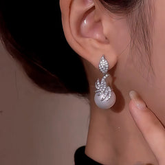 Model showcasing the dangle and style of the 14K Gold-Plated Zircon Leaf Pearl Earrings