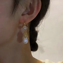 Front view of gold leaf teardrop pearl drop earring worn on ear